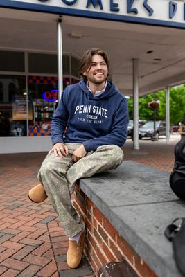 a man sitting on a brick wall in front of a store