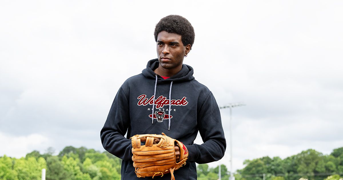 a man in a black hoodie holding a baseball glove
