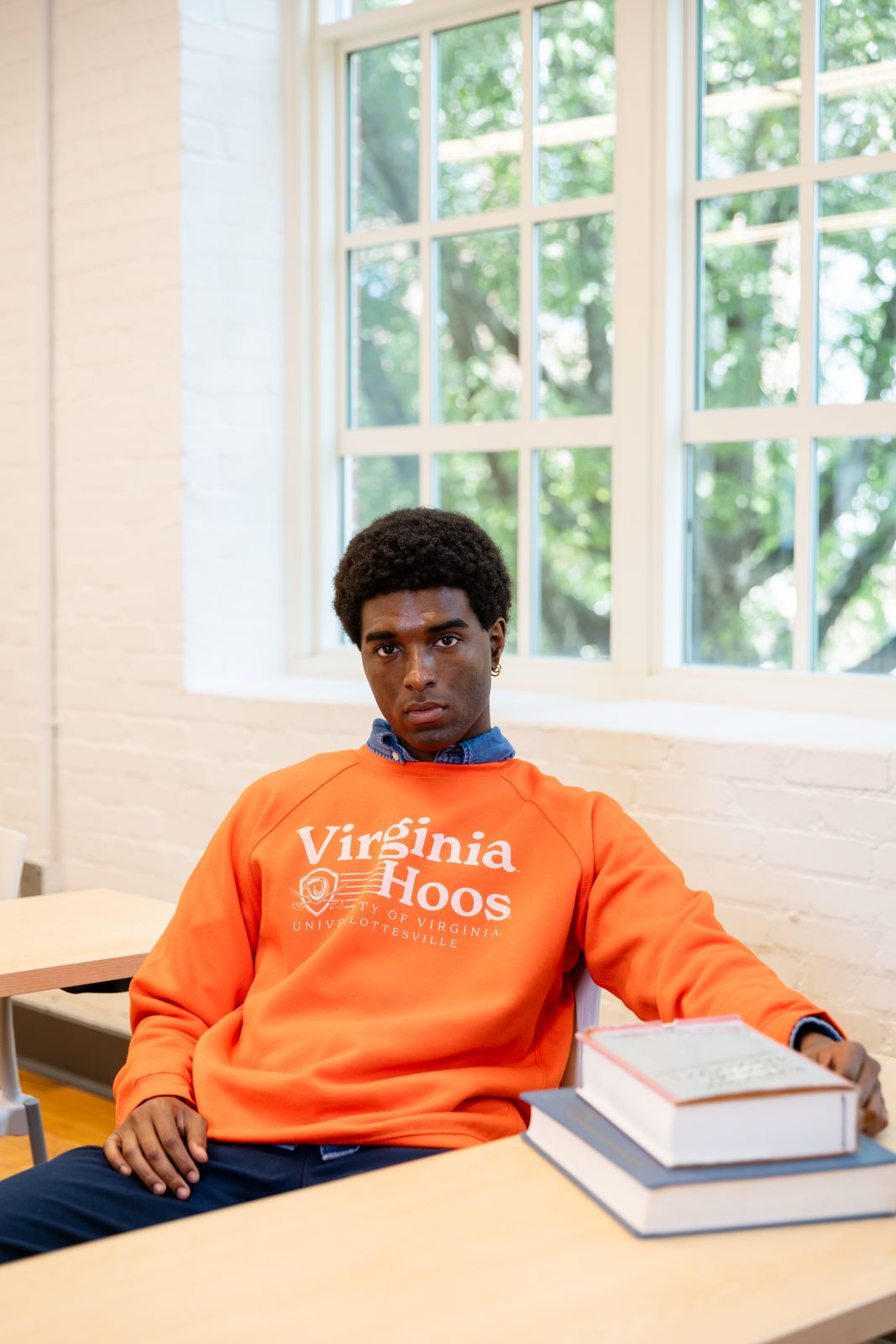a man in an orange sweatshirt sitting at a table