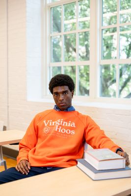 a man in an orange sweatshirt sitting at a table