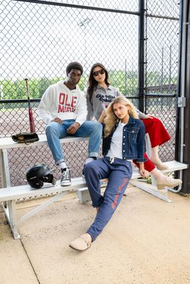 three people sitting on a bench in front of a fence