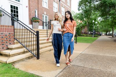 two women walking down a sidewalk next to a set of stairs
