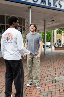 two men standing outside of a store talking to each other