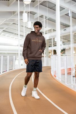 a man standing on a track wearing a brown hoodie