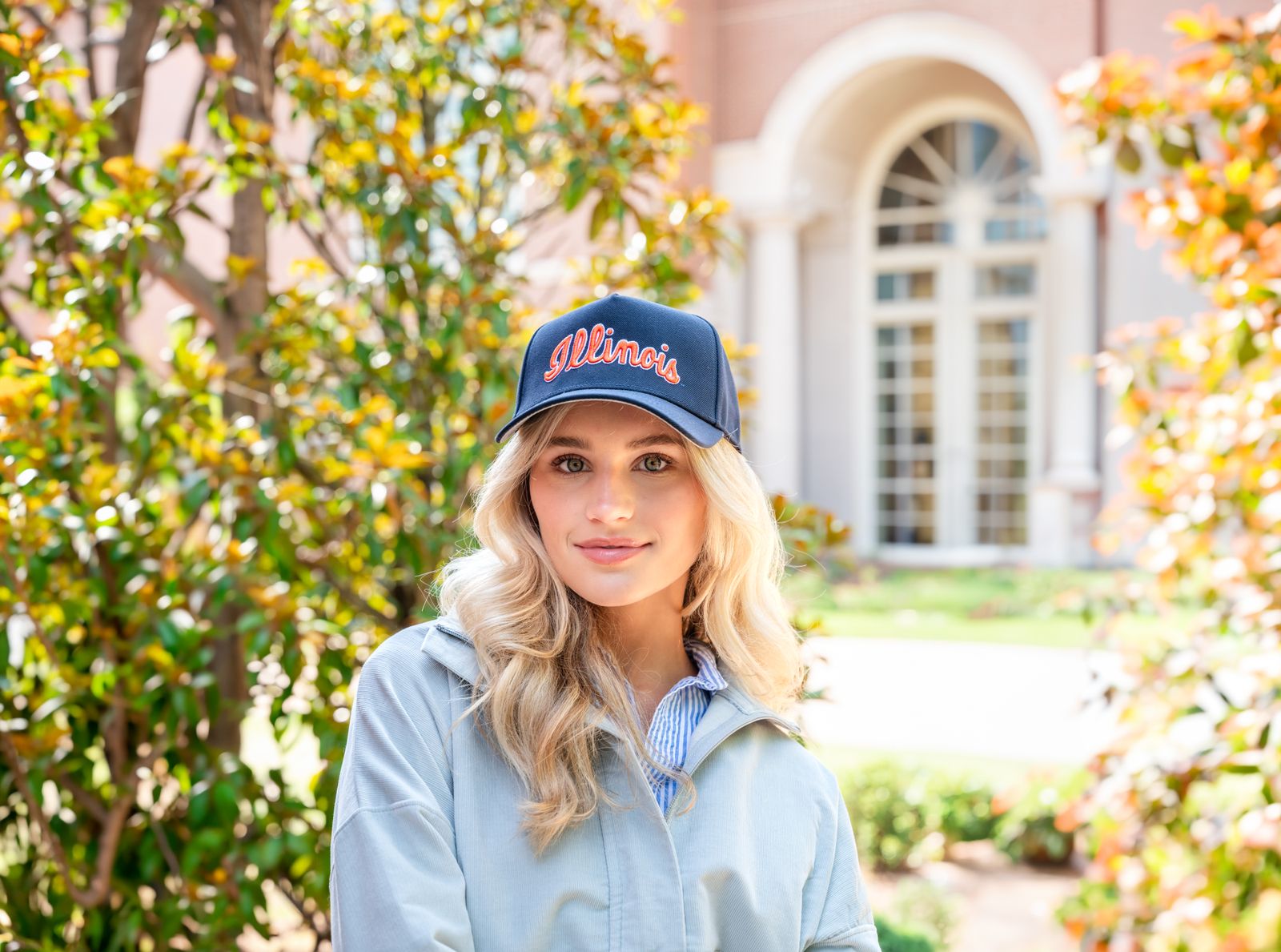a woman standing in front of a tree wearing a hat