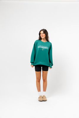 a woman wearing a green sweatshirt and black shorts