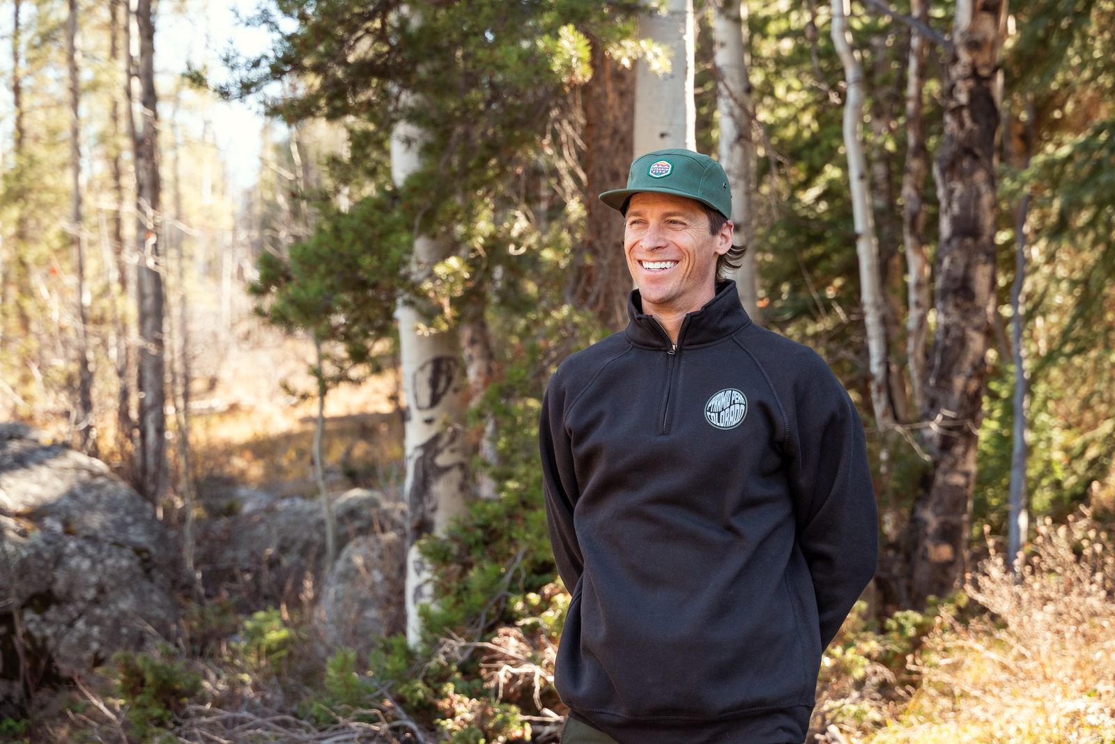 a man standing in the woods wearing a green hat