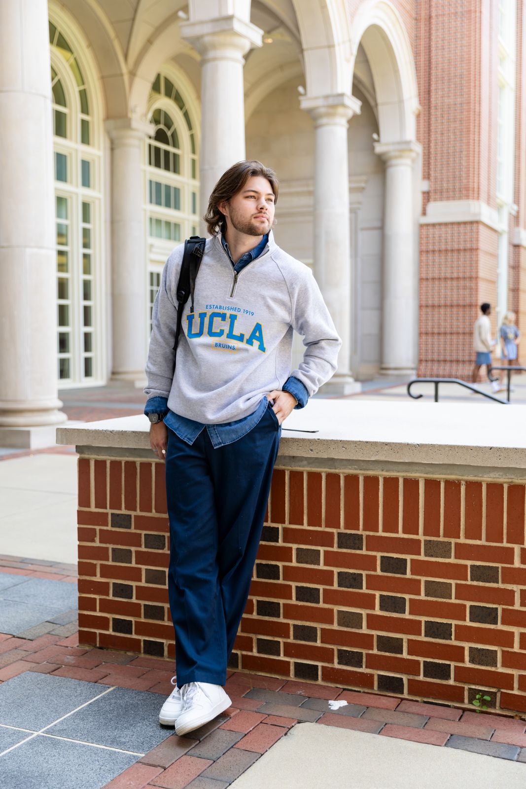 a man leaning against a brick wall in front of a building