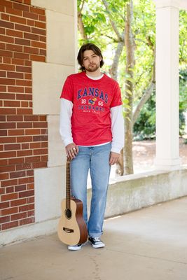 a man with a guitar standing in front of a building