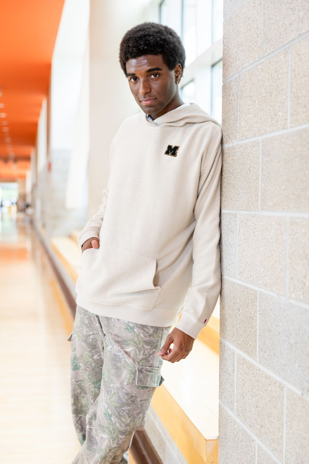 a man leaning against a wall wearing a sweatshirt and sweatpants