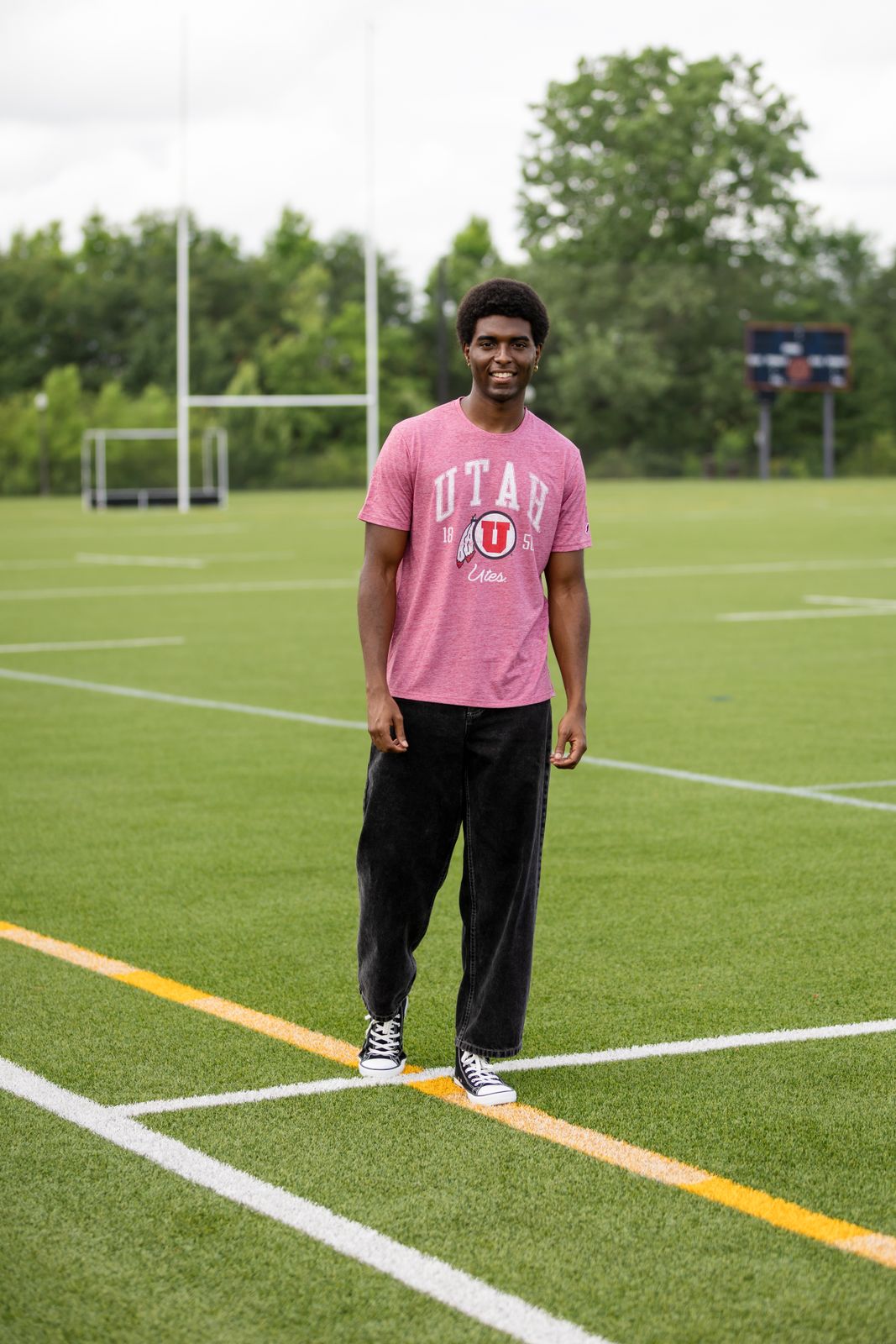 a man in a pink shirt standing on a soccer field