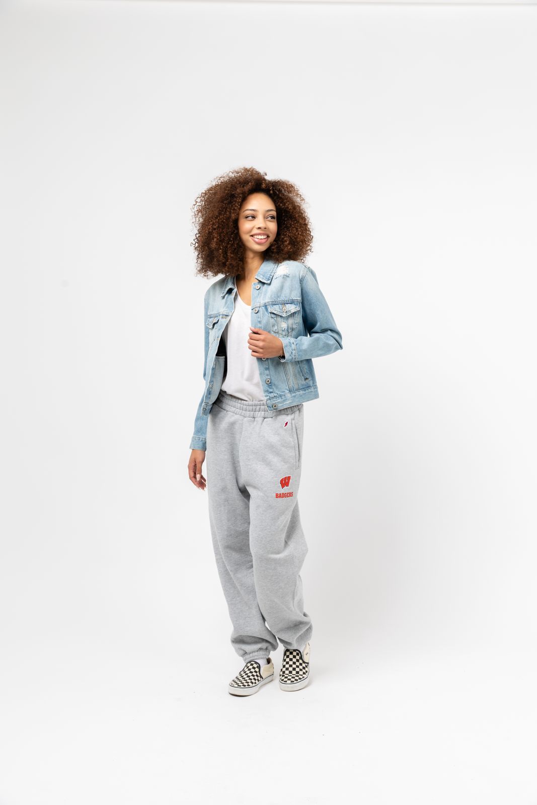 a woman in a denim jacket and sweatpants posing for a picture