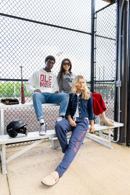 three people sitting on a bench in front of a fence