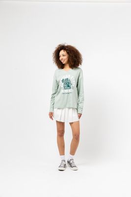 a woman wearing a green sweatshirt and white skirt