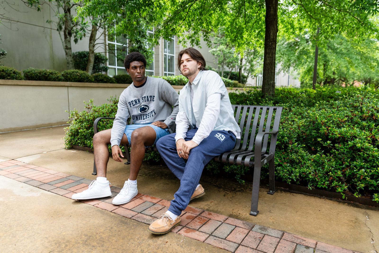 two young men sitting on a bench in a park