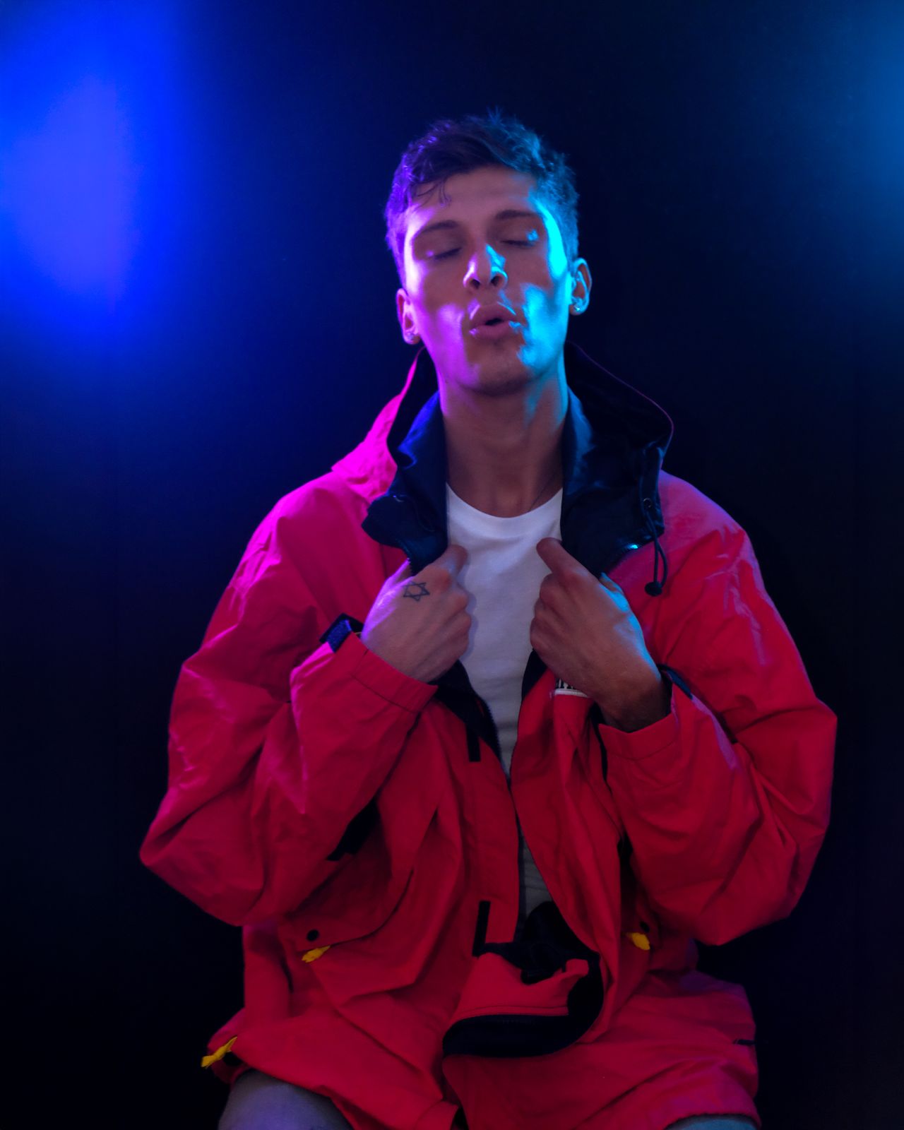 a man in a red jacket sitting on a stool