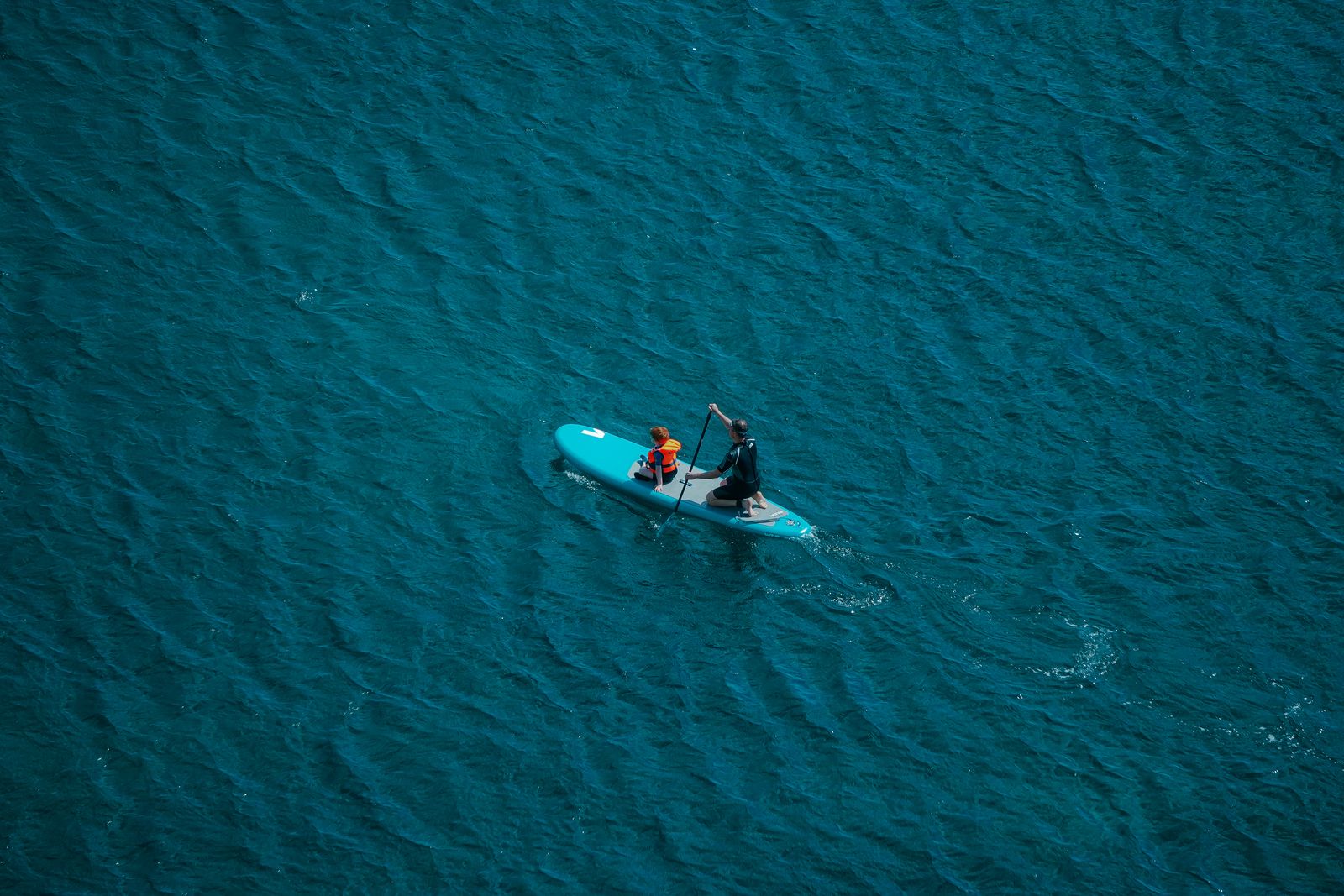 two people in a small boat in the middle of the ocean