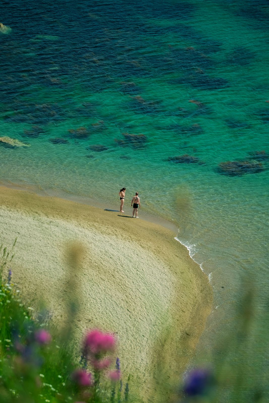 a couple of people standing on top of a sandy beach