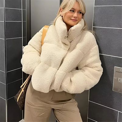 a woman in a white coat leaning against a wall