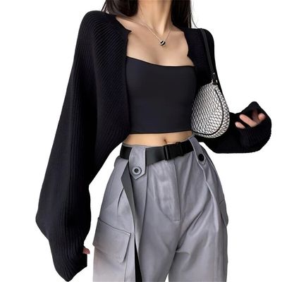 a woman wearing a black crop top and silver pants