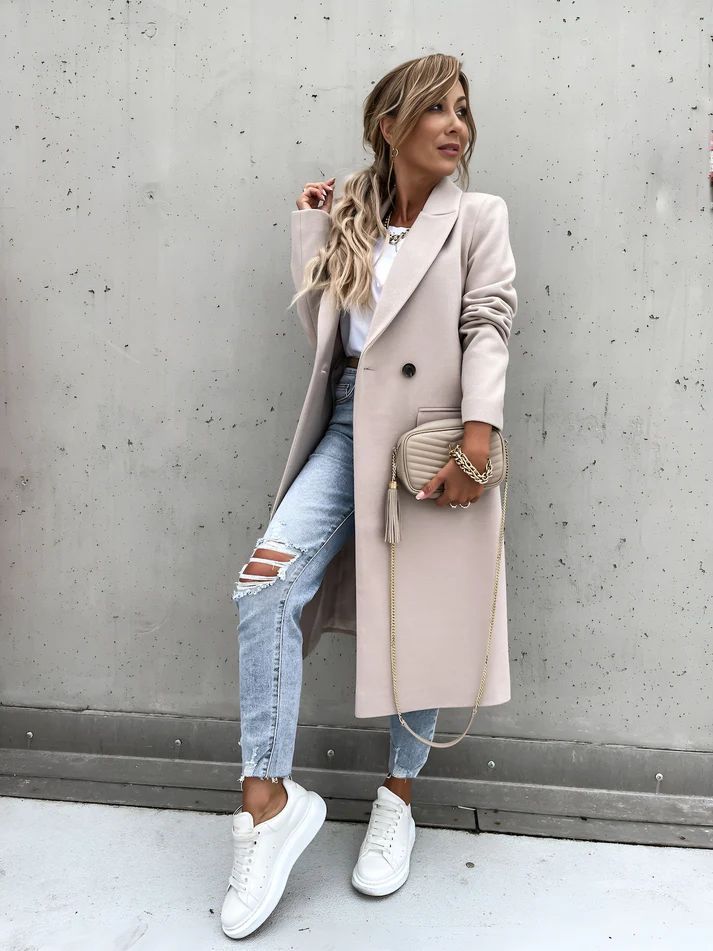 a woman wearing ripped jeans and a trench coat