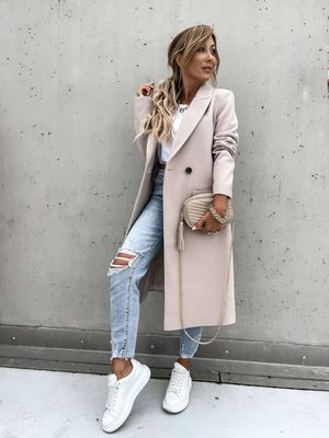 a woman wearing ripped jeans and a trench coat