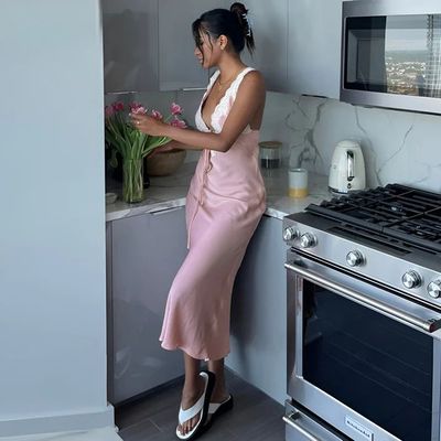 a woman in a pink dress standing in a kitchen