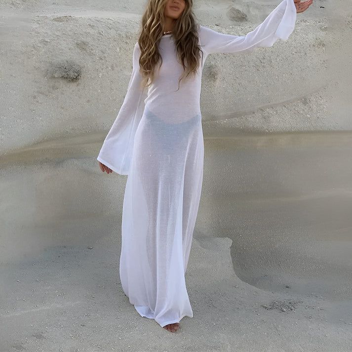 a woman in a white dress standing in the sand