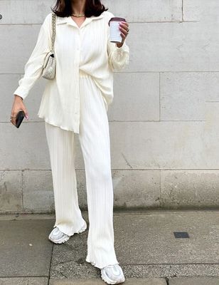 a woman standing on a sidewalk holding a cup of coffee