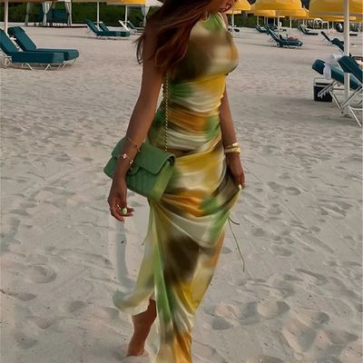 a woman in a dress and hat walking on the beach