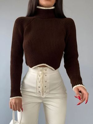 a woman wearing a brown sweater and white pants