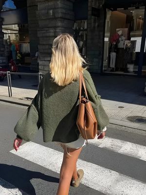 a woman walking across a street holding a purse