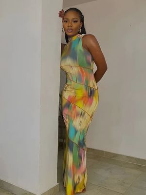 a woman in a colorful dress leaning against a wall