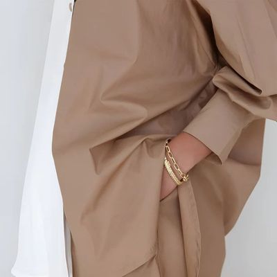 a woman wearing a brown shirt and a gold bracelet
