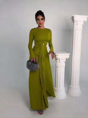 a woman in a green dress standing next to a white column