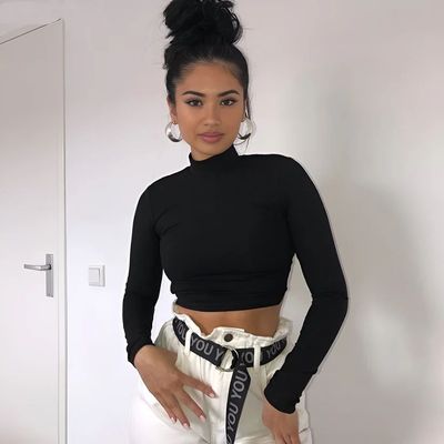 a woman wearing white pants and a black top