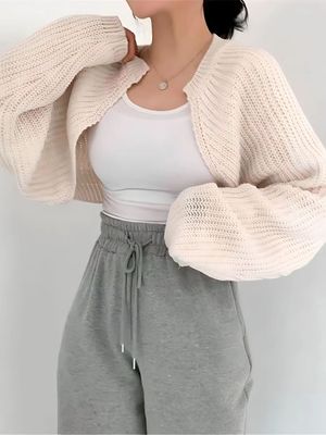 a woman wearing a white sweater and grey sweatpants