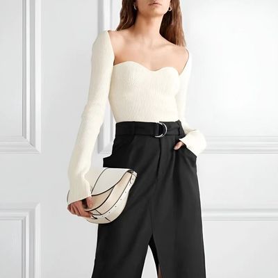 a woman wearing a white sweater and black pants