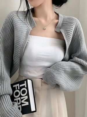 a woman wearing a white top and a gray cardigan