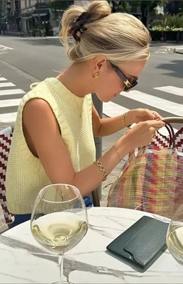 a woman sitting at a table in front of a wine glass