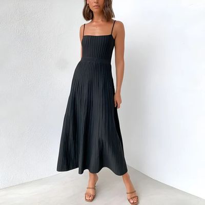 a woman in a black dress standing in front of a white wall