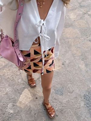 a woman wearing a white shirt and a colorful skirt