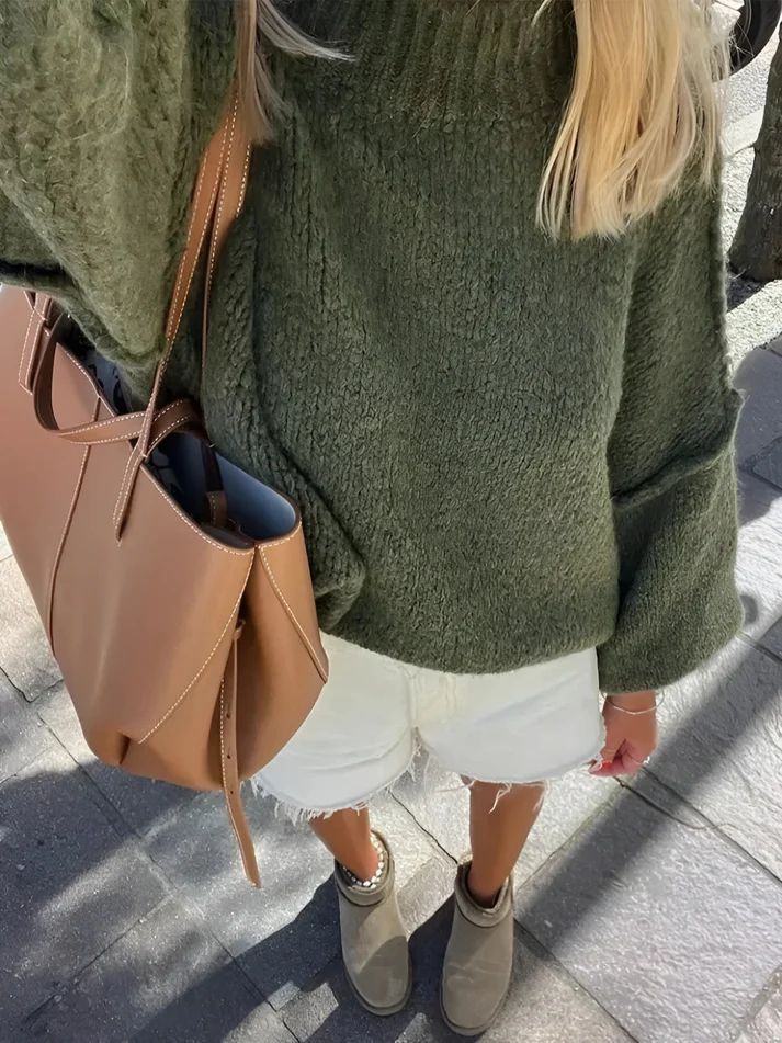 a blonde woman wearing a green sweater and white shorts