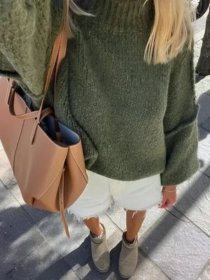 a blonde woman wearing a green sweater and white shorts