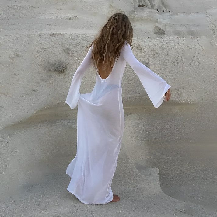 a woman in a white dress walking in the sand