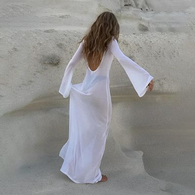 a woman in a white dress walking in the sand