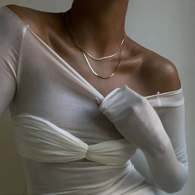 a woman wearing a white shirt and a gold necklace