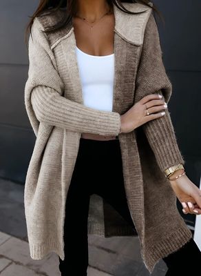 a woman wearing a tan sweater and black pants
