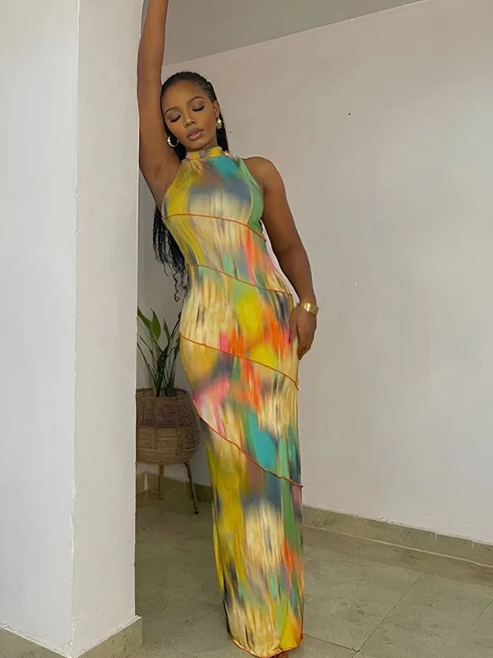 a woman in a colorful dress leaning against a wall
