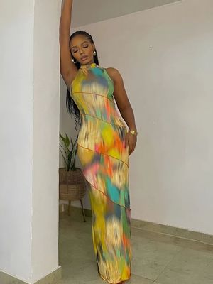 a woman in a colorful dress leaning against a wall